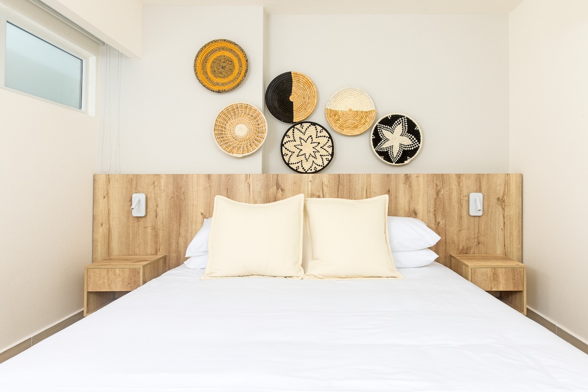 Bedroom with woven basket decor and light wood headboard in Penthouse 900-7