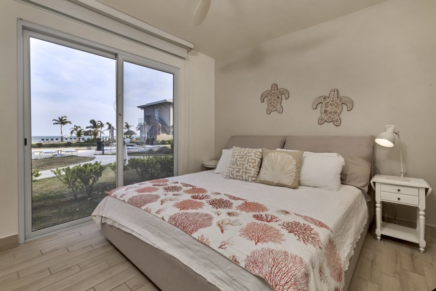 Master bedroom with ocean and pool view through sliding glass door in Villa C13-PBB at Playa Caracol