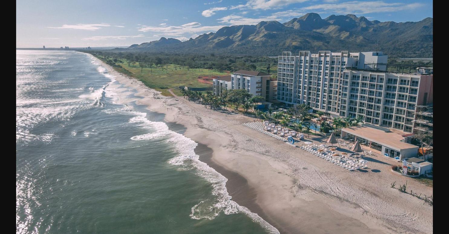 Aerial view of Playa Caracol resort on Panama's Pacific coast, showing the beach, hotel, and mountains