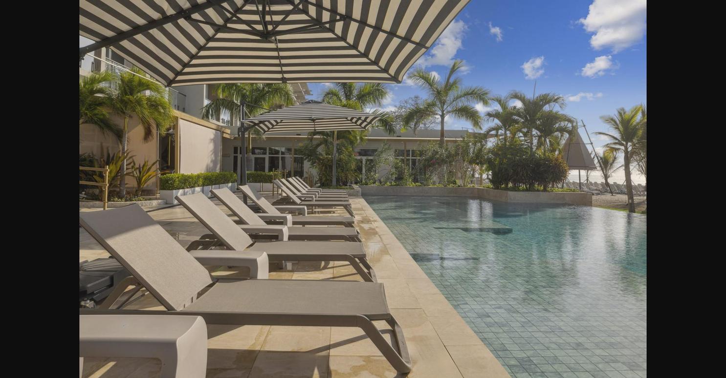 Poolside lounge area with umbrellas and palm trees at Playa Caracol